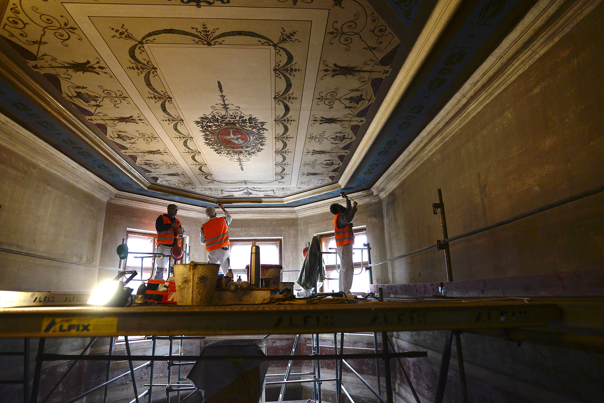 Restaurátoři obnovují zdobení stropu nad schodištěm