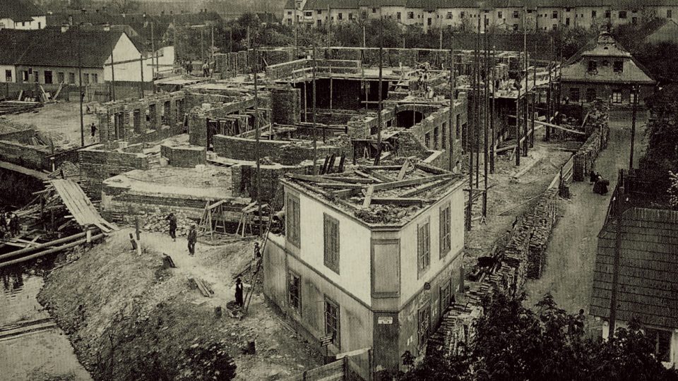 Staveniště divadla v roce 1907 v popředí s bouraným objektem
