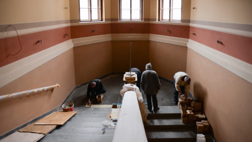 Řemeslníci na schodišti pracují na pokládání mozaikové dlažby (únor 2019)