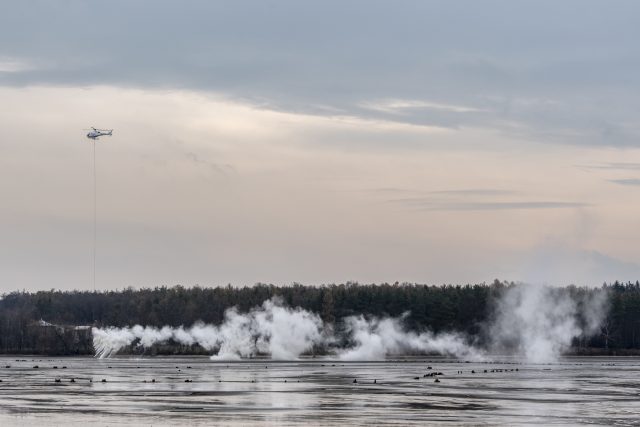 Specializovaná firma shazuje z vrtulníku na dno rybníka tuny nehašeného vápna | foto: David Taneček,  ČTK